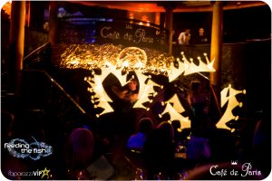 Two performers on stage at Café de Paris spin LED light wands. They display LED graphics of gold crowns in the air.